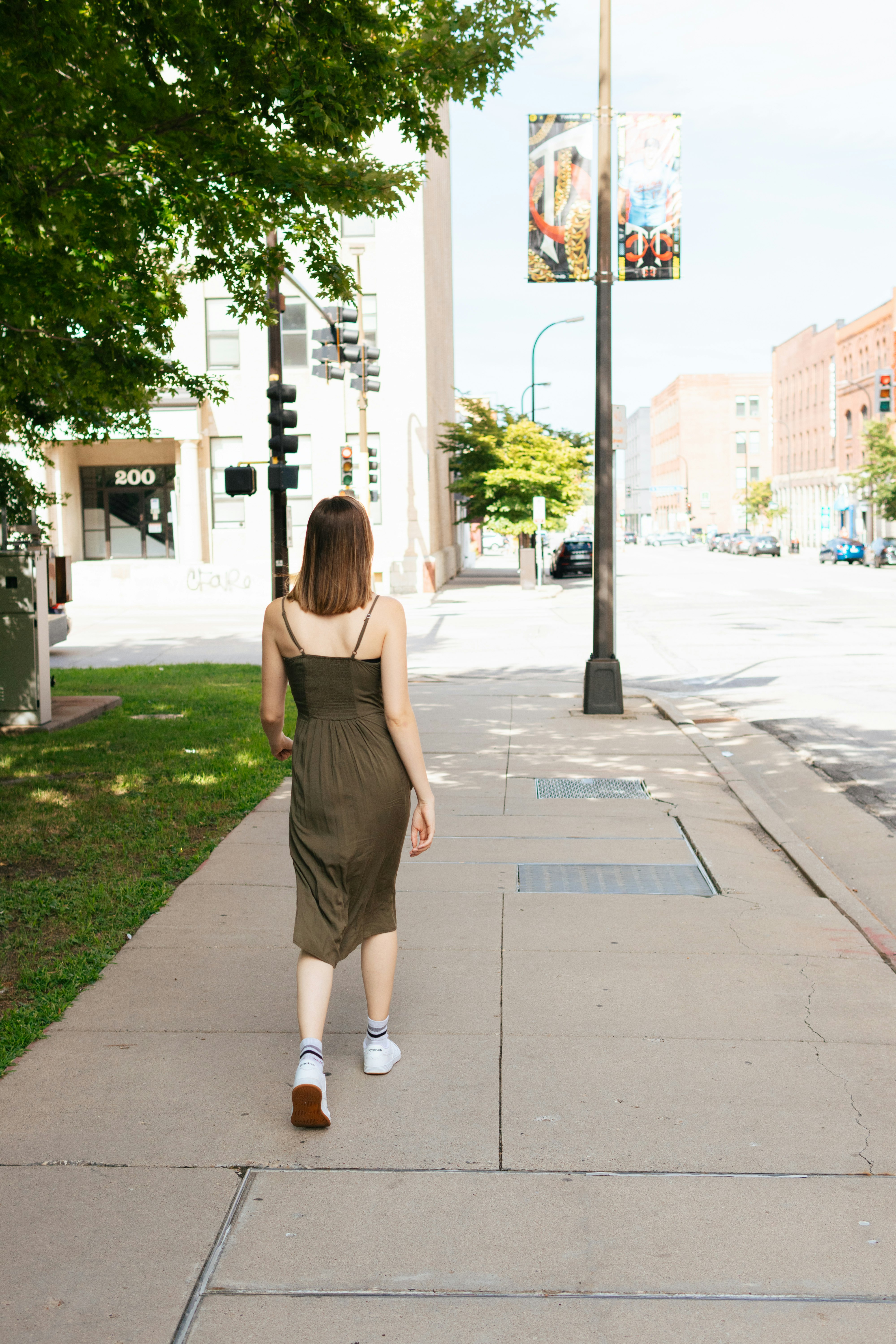 woman in black dress walking on sidewalk during daytime